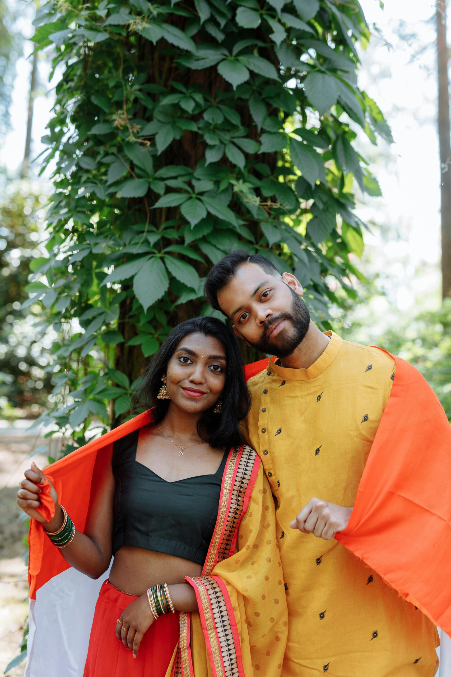 Smiling Indian couple outdoors in traditional dress, wrapped in the Indian flag.